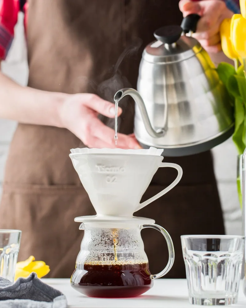 Close-up of coffee brewing with a pour-over method in a sunny kitchen setting.