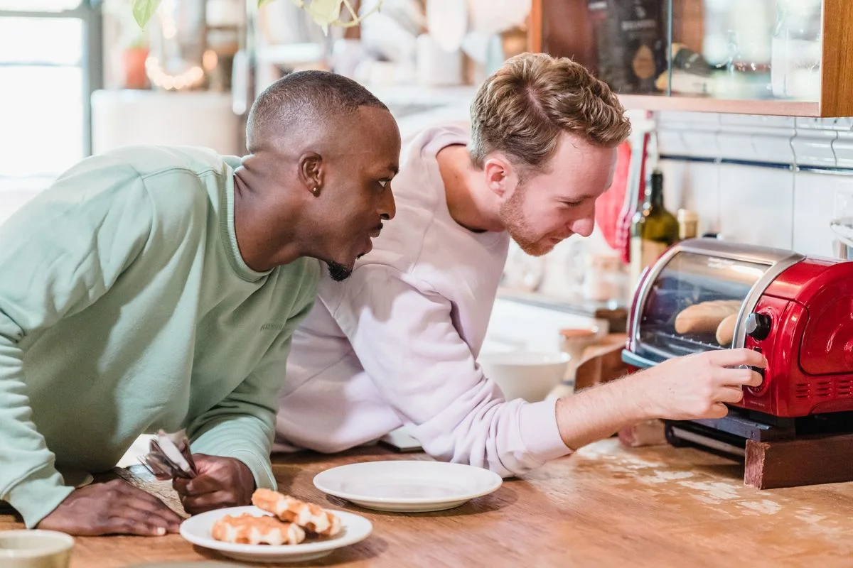 Two men making breakfast with a toaster in a cozy kitchen setting.