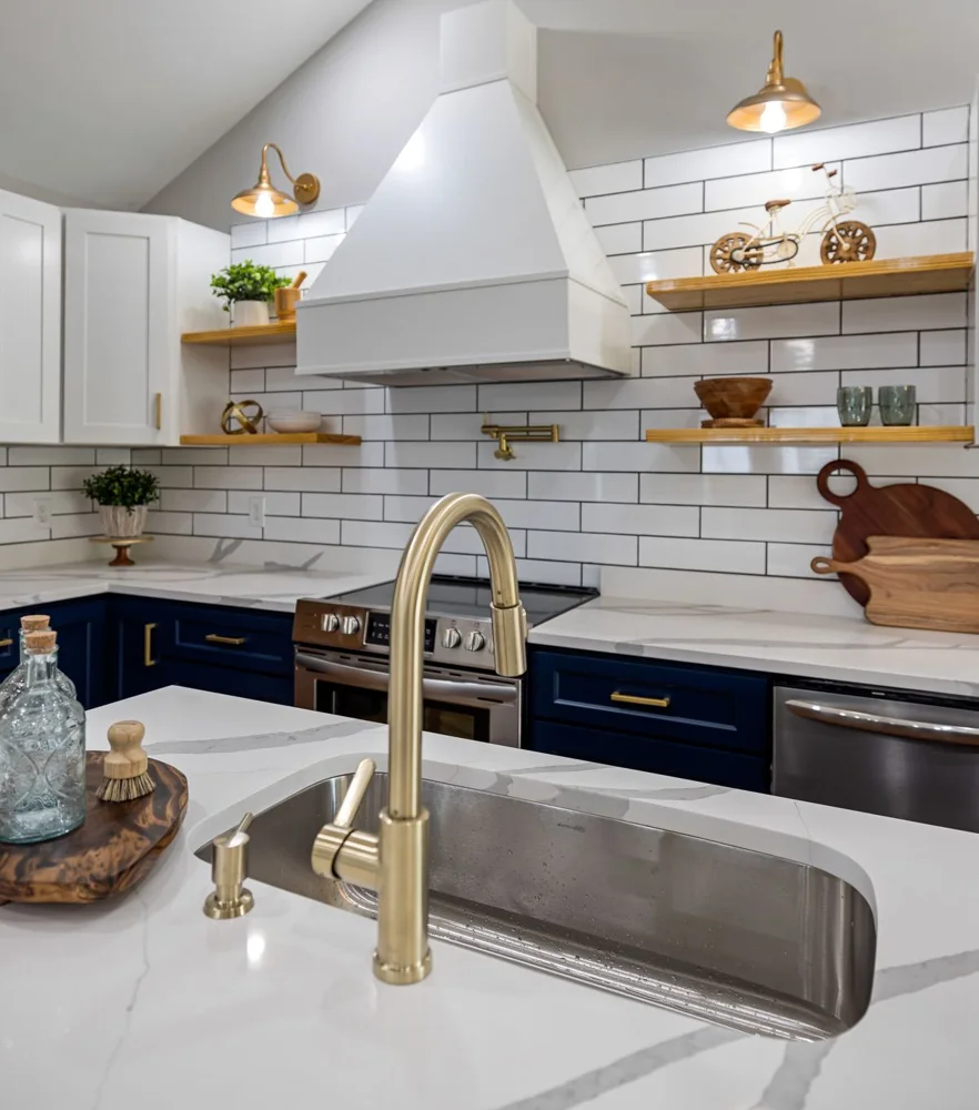 Stylish kitchen featuring marble countertops, brass fixtures, and open shelving.