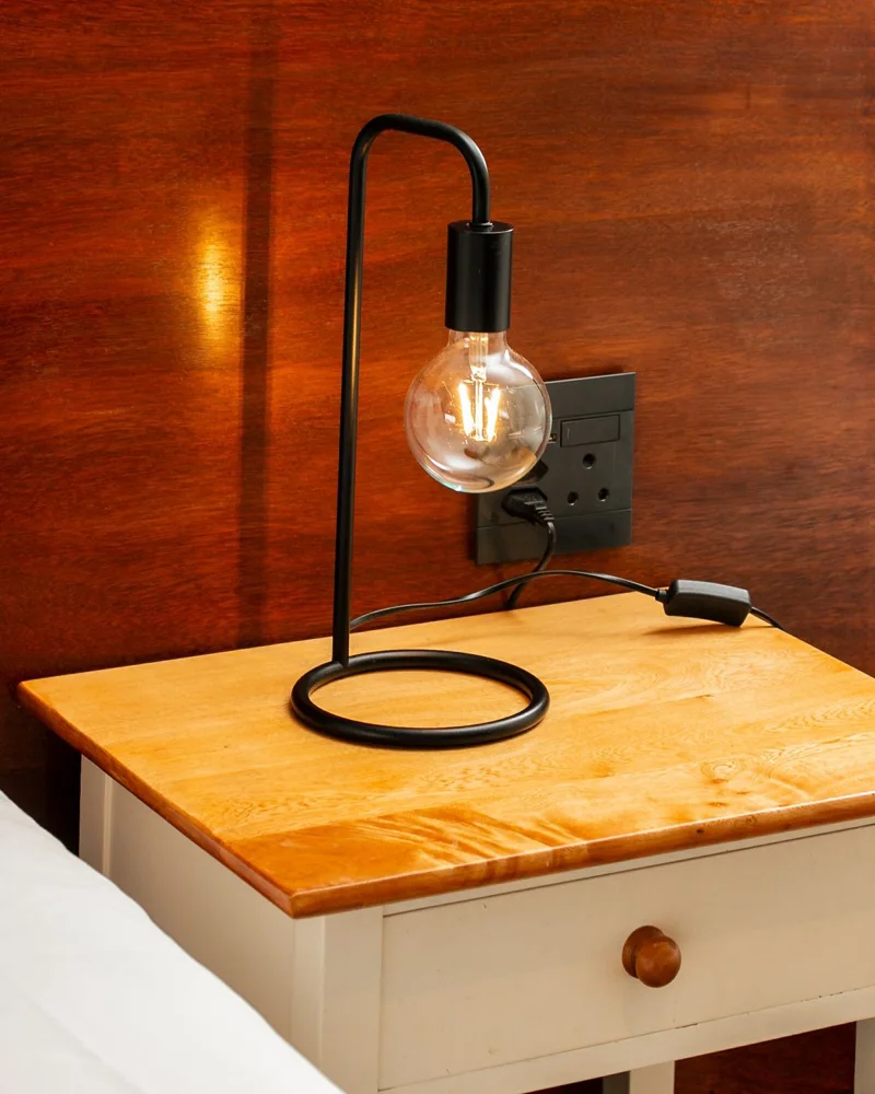 Modern lamp on a wooden bedside table with cozy ambiance.