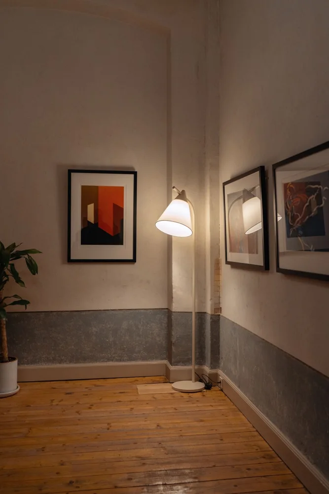 Elegantly designed corner room featuring art pieces and a soft-glow floor lamp casting aesthetic shadows.