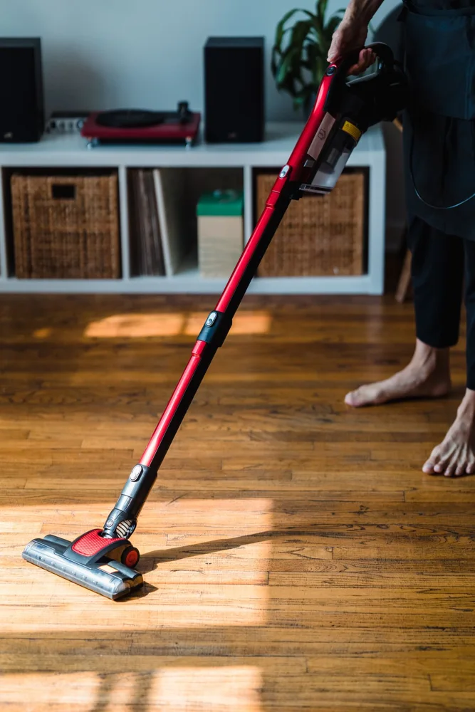 Person vacuuming a wooden floor with a modern appliance, highlighting efficient home cleaning.