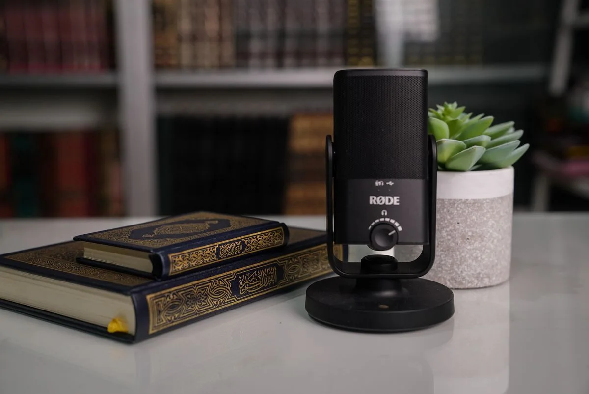 Close-up of books with a Røde microphone and succulent on a desk.