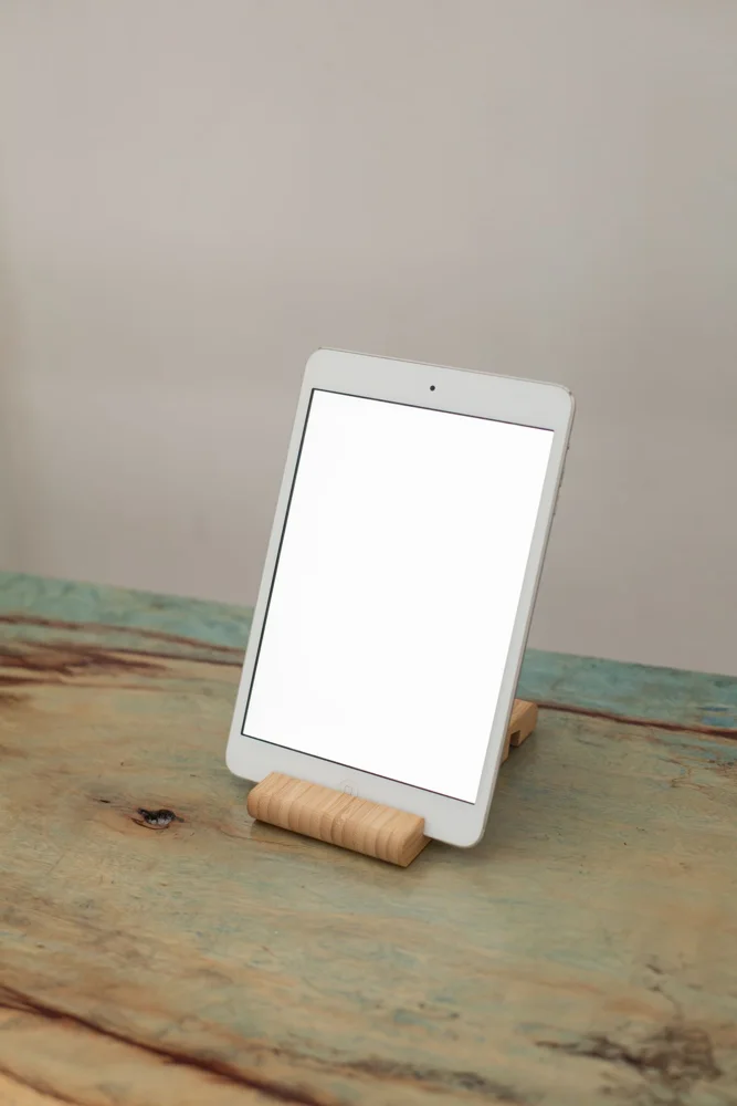 A tablet with a blank screen on a wooden stand, ideal for mockups.