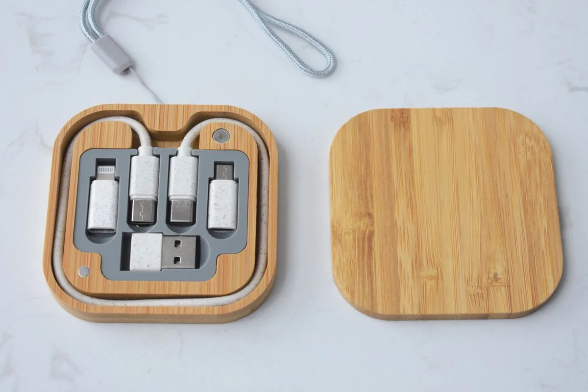 Bamboo tech organizer box with USB cables and adapters on a white surface.