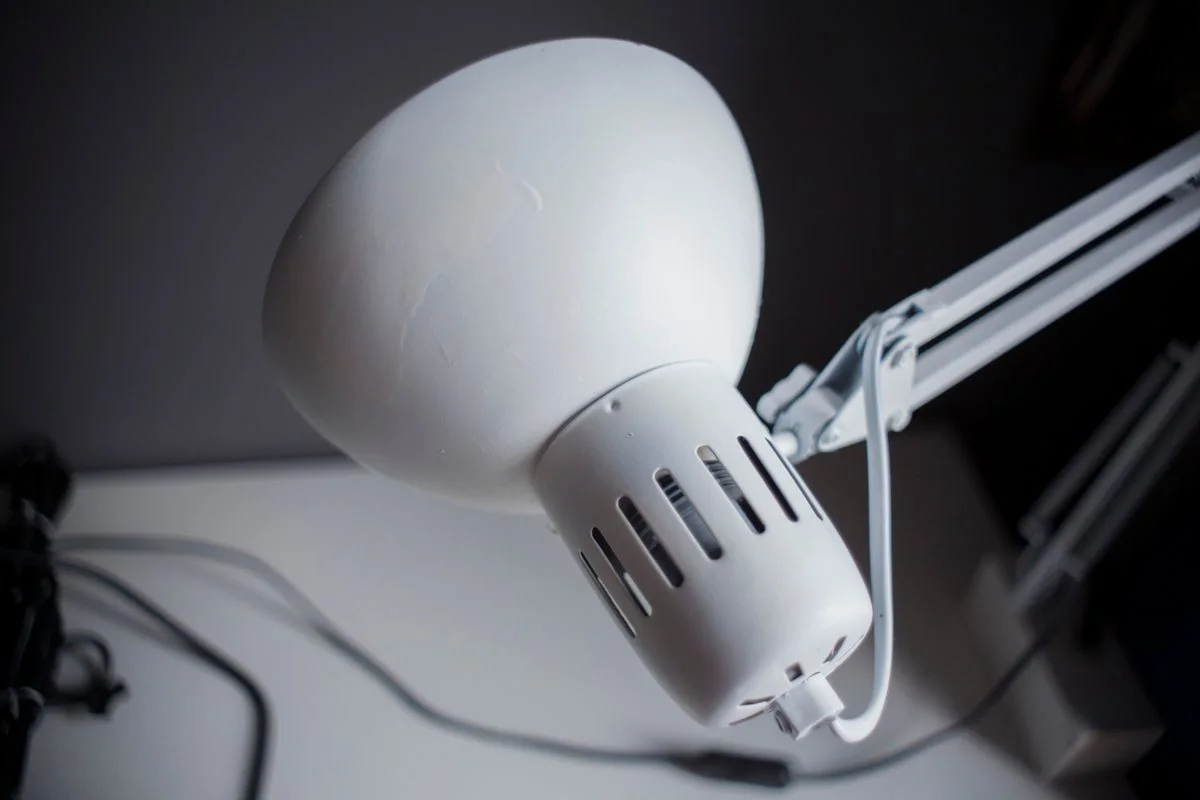Close-up of a white desk lamp in a modern office, emphasizing its sleek design and functionality.