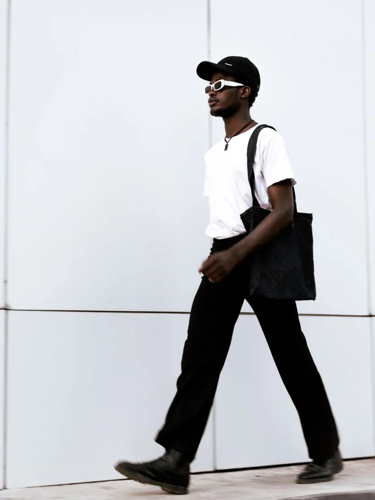 Fashionable adult walking with tote bag in urban setting, showcasing casual style.